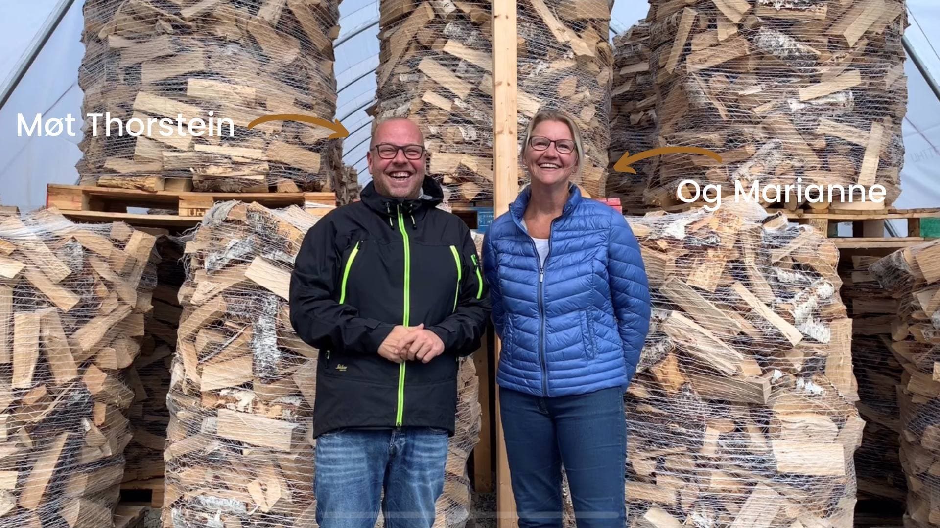 Thorstein og Marianne foran stablede paller med bjørkeved i tørketunnelen på anlegget i Drøbak